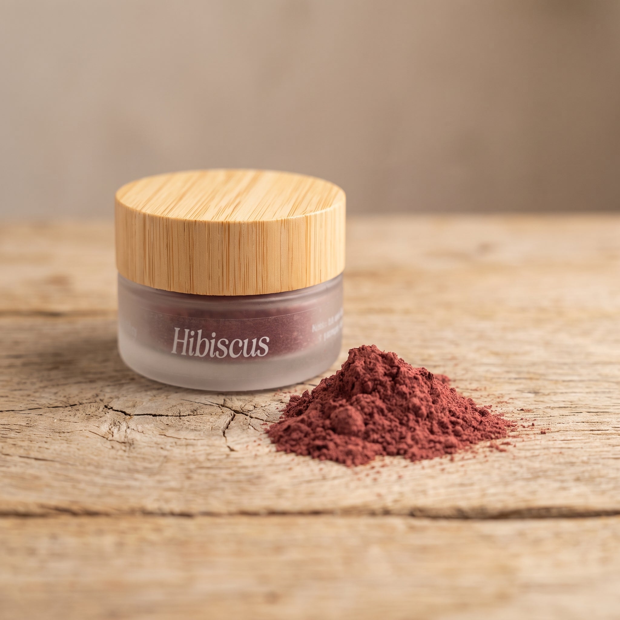 Jar of Eliézer Clay organic hibiscus powder with a mound of pink powder on a pale oak table